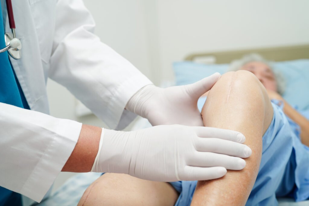 doctor checking asian elderly woman patient with scar knee replacement surgery hospital